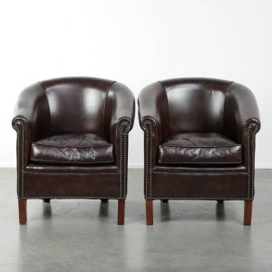 In goede staat verkerende set van twee donkere rundleren clubfauteuils met een tijdloos en stijlvol design in Engelse stijl