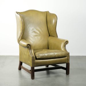 Karaktervolle, luxe oude en sierlijke groene rundleren oorfauteuil in een klassieke Engelse landhuis stijl