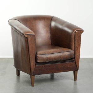 Leuke en strak Art Deco vormgegeven schapenleren clubfauteuil afgewerkt met zwarte biezen