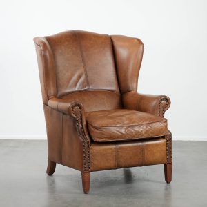 Tijdloze cognac kleurige oorfauteuil in Engelse stijl gemaakt van rundleer afgewerkt met siernagels en mooie details