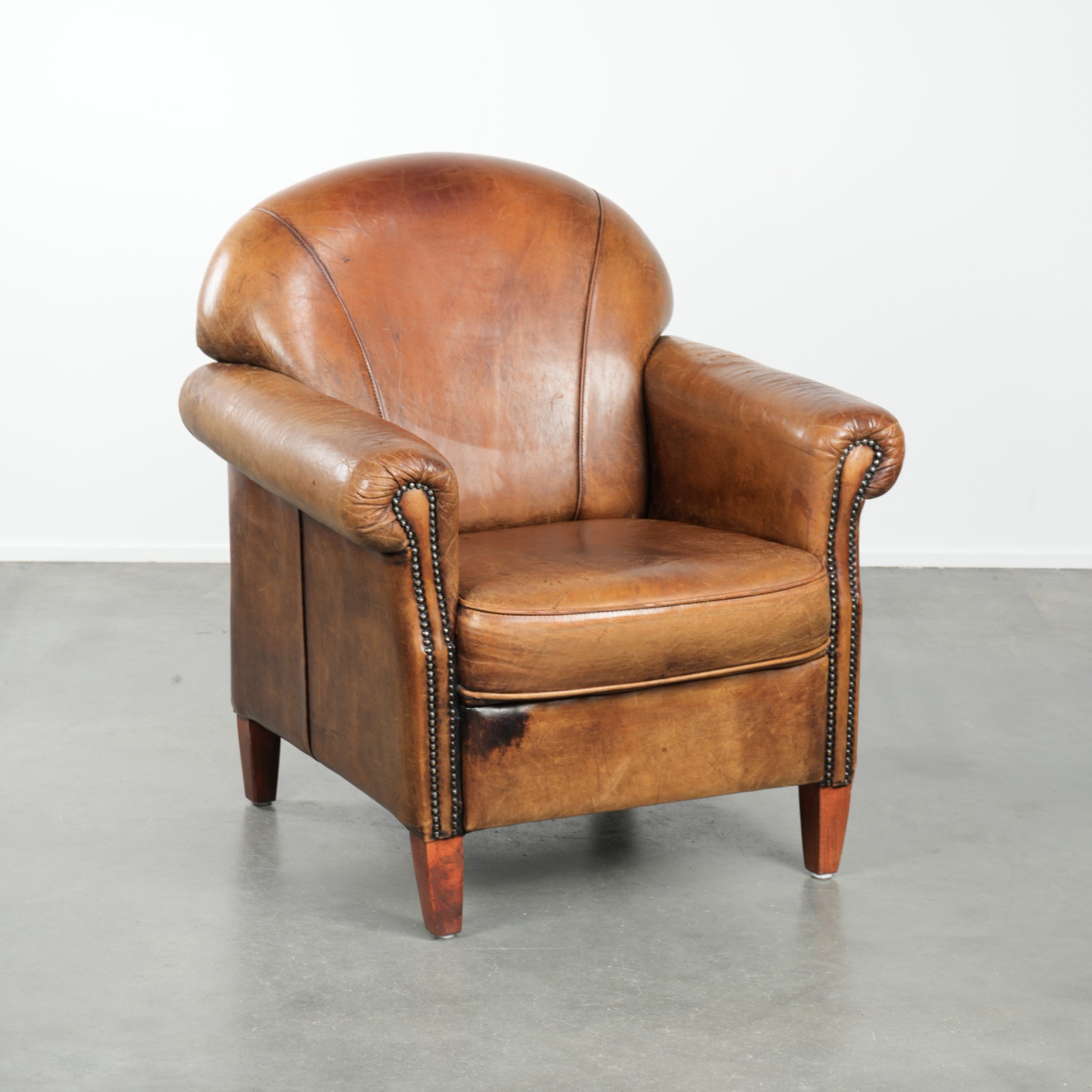 Karaktervolle schapenleren fauteuil met een mooie vintage look en een afwerking met siernagels