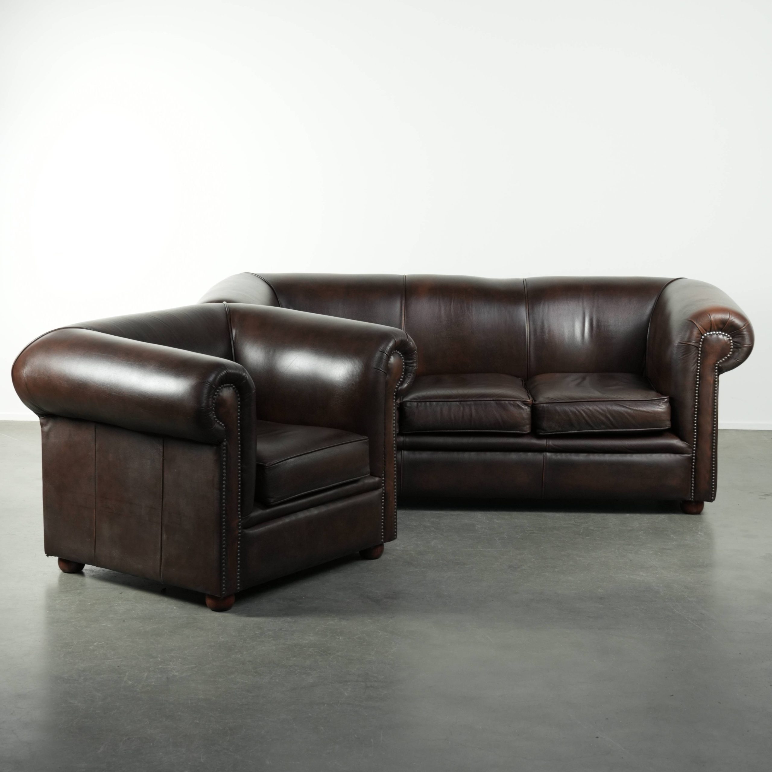 Luxe bruine rundleren set bestaande uit een gladde chesterfield bank en fauteuil met een tijdloze Engelse uitstraling