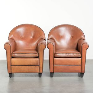 Set van twee Bart van Bekhoven design fauteuils van schapenleer met een ronde rug en zwarte biezen