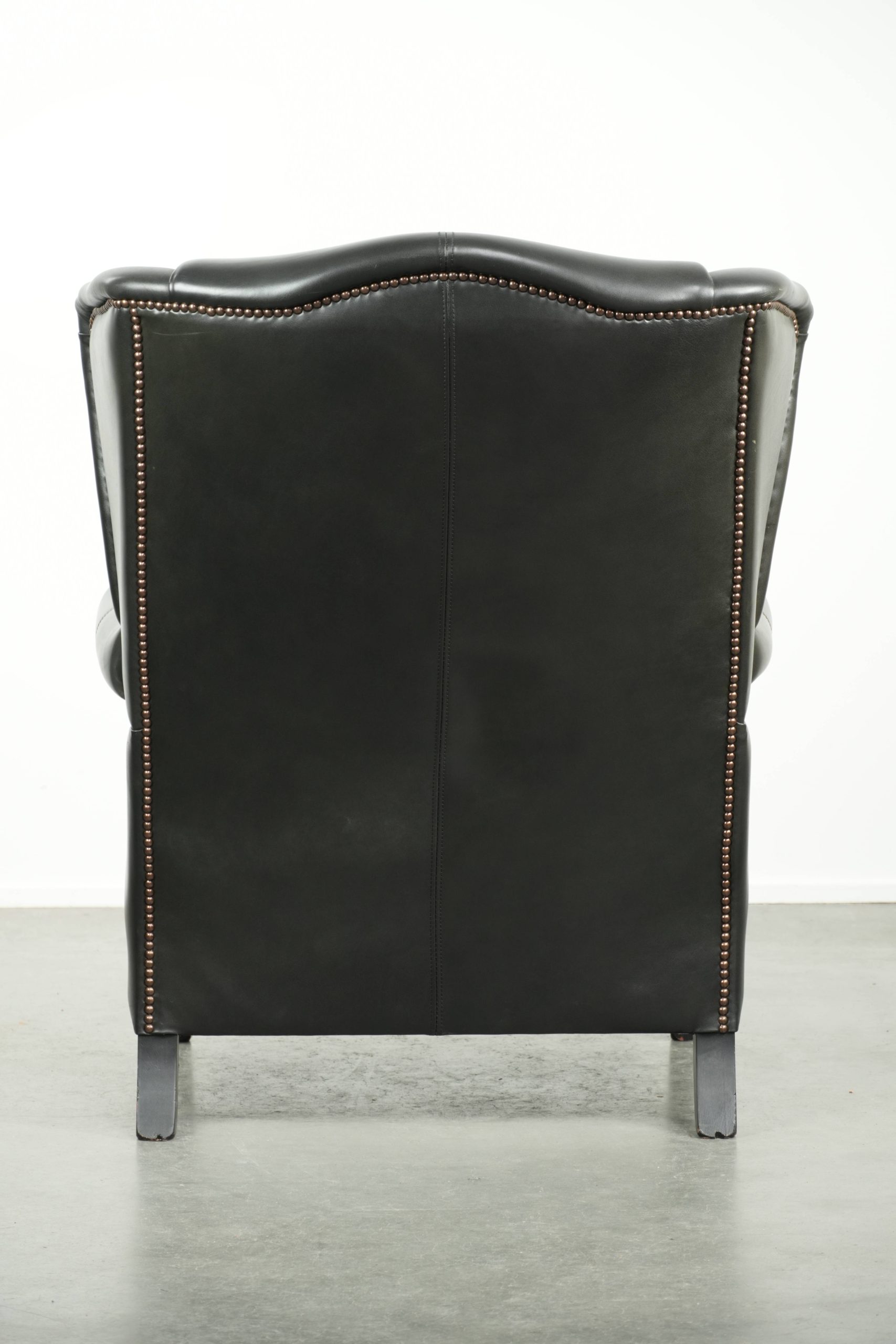 Zwarte rundleren oorfauteuil in een klassiek Engelse stijl afgewerkt met siernagels - Afbeelding 4