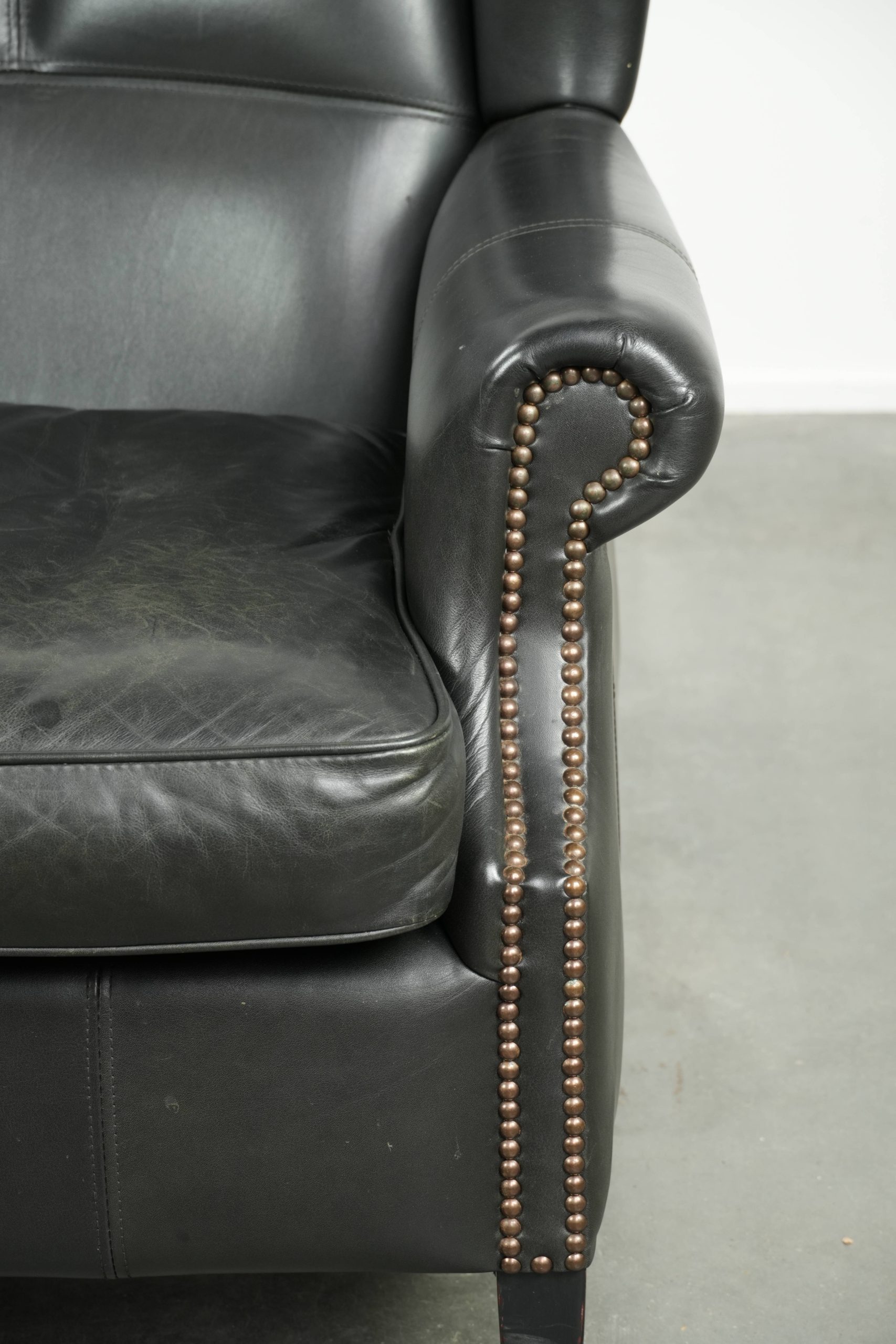 Zwarte rundleren oorfauteuil in een klassiek Engelse stijl afgewerkt met siernagels - Afbeelding 9