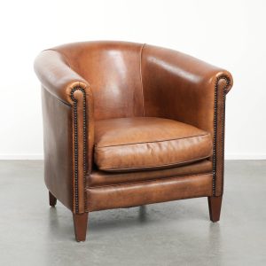 Karaktervolle schapenleren clubfauteuil met een warme cognac kleur afgewerkt met siernagels