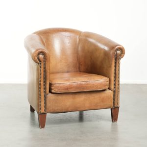 Karaktervolle vintage schapenleren clubfauteuil met mooie kleuren en afgewerkt met siernagels