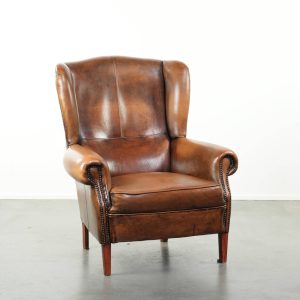 Comfortabele oorfauteuil gemaakt van schapenleer afgewerkt met siernagels en een karaktervolle uitstraling in Engelse stijl
