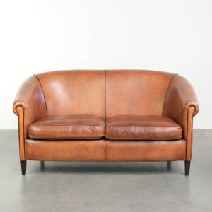 Mooie schapenleren 2 zits bank met een warme cognac bruine kleurstelling en een prachtig afwerking met zwarte biezen