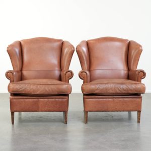 Set van twee mooie rundleren oorfauteuils in Engelse stijl met meekleurende biezen en een karaktervolle uitstraling