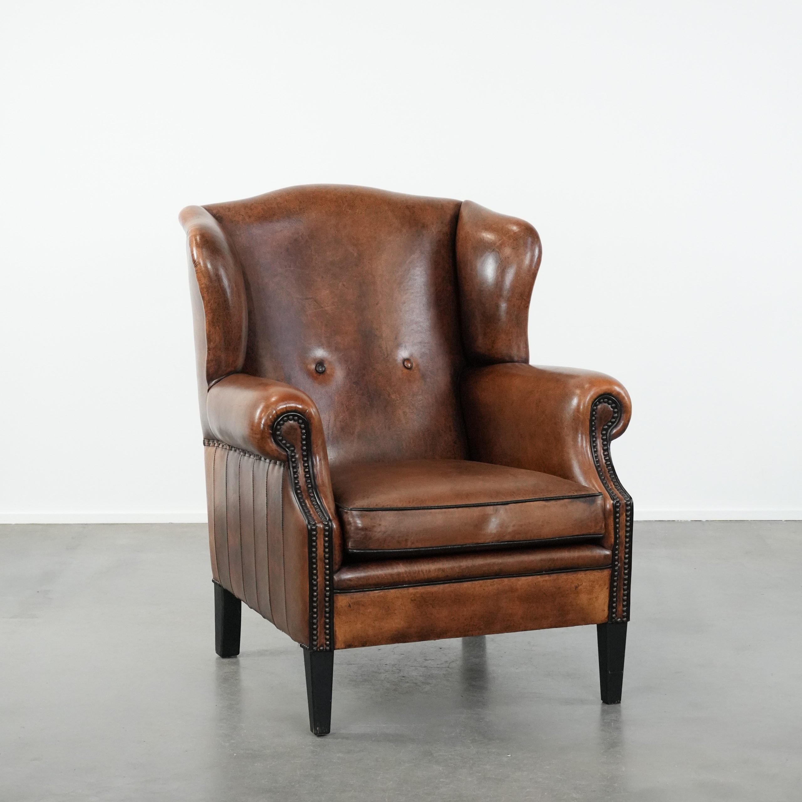 Tijdloze en comfortabele schapenleren oorfauteuil met mooie kleuren en een afwerking met siernagels en zwarte biezen
