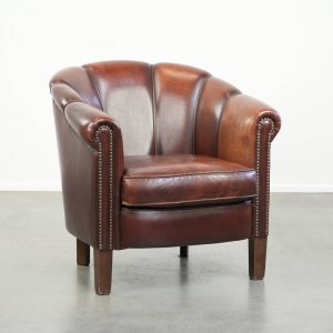 Karaktervolle vintage schapenleren clubfauteuil met een origineel design afgewerkt met siernagels
