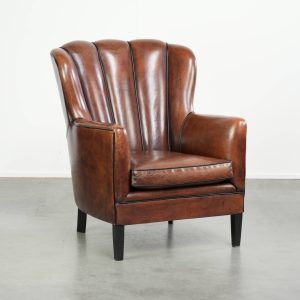 Unieke schapenleren armchair met warme diepe kleuren afgewerkt met zwarte biezen