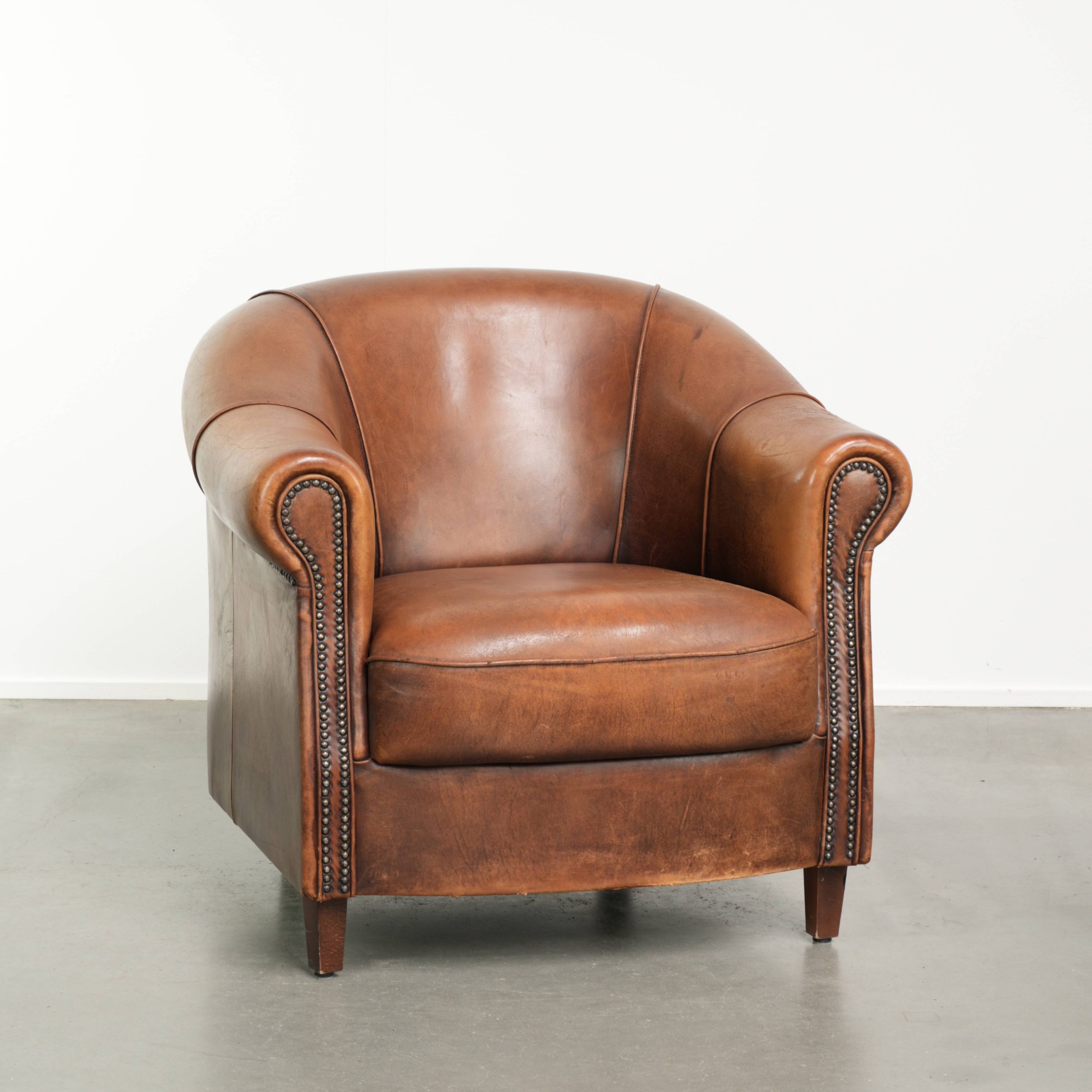 Mooie cognac kleurige schapenleren clubfauteuil met een vast zitkussen en een luxe uitstraling