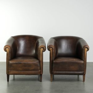 Stoere set van twee schapenleren clubfauteuils in Engelse stijl afgewerkt met biezen