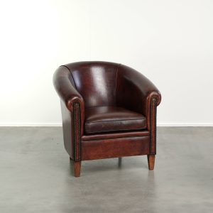 Stoere vintage schapenleren clubfauteuil met mooie kleuren en een luxe afwerking met siernagels en zwarte biezen