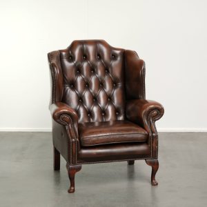 Sierlijke rundleren chesterfield oorfauteuil in een donker bruine kleur afgewerkt met siernagels
