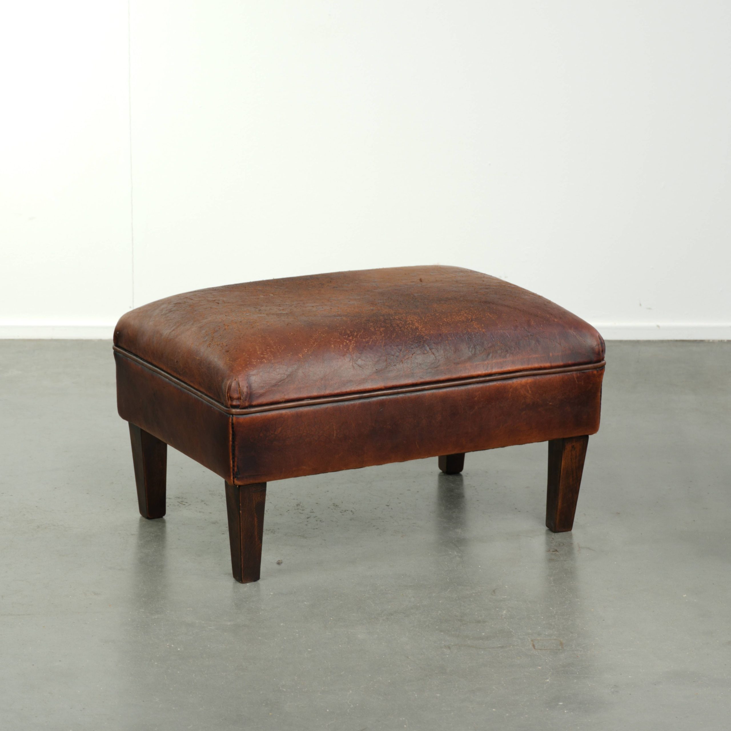 Vintage schapenleren hocker in een bruine kleurstelling met een tijdloze uitstraling