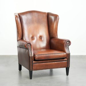 Schapenleren oorfauteuil in een warme cognac kleur met een verfijnde afwerking van siernagels