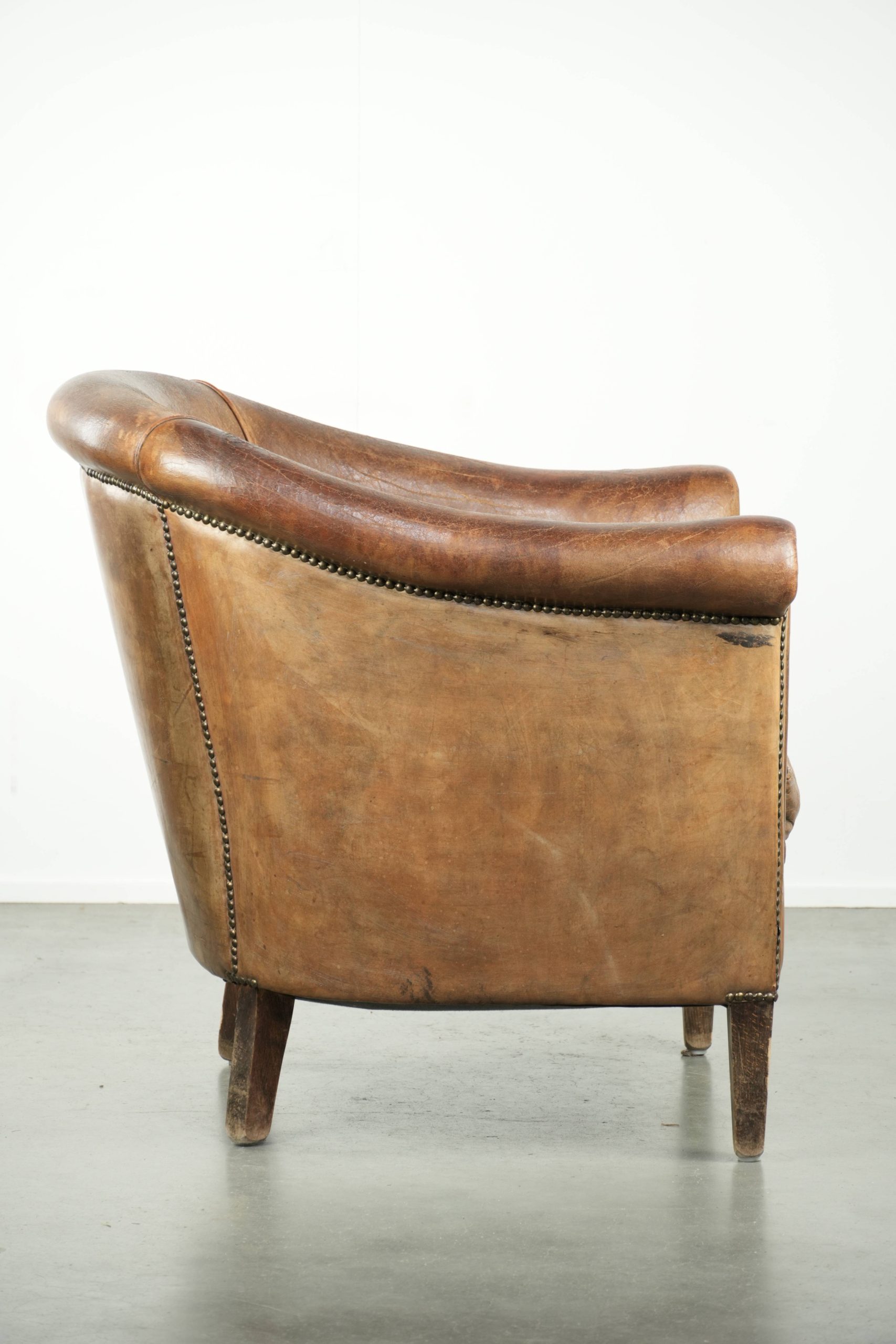 Vintage schapenleren clubfauteuil afgewerkt met siernagels en een elegante uitstraling - Afbeelding 3
