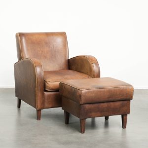 Tijdloze set van een schapenleren armchair en hocker afgewerkt met meekleurende biezen en een strak design