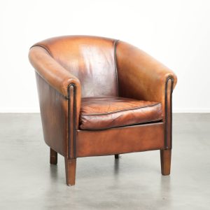 Vintage schapenleren clubfauteuil met een prachtige kleurstelling afgewerkt met zwarte biezen en een comfortabele zit