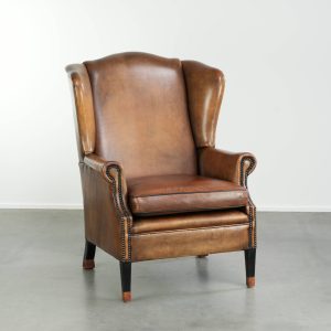 Elegante schapenleren oorfauteuil met een prachtige kleurstelling en een mooi patina afgewerkt met siernagels
